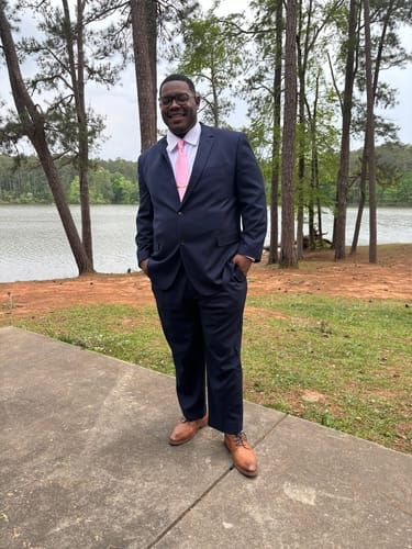 Customer Justin W. wearing the Modern Navy Blue 2 Button Suit with a pink tie by a lake