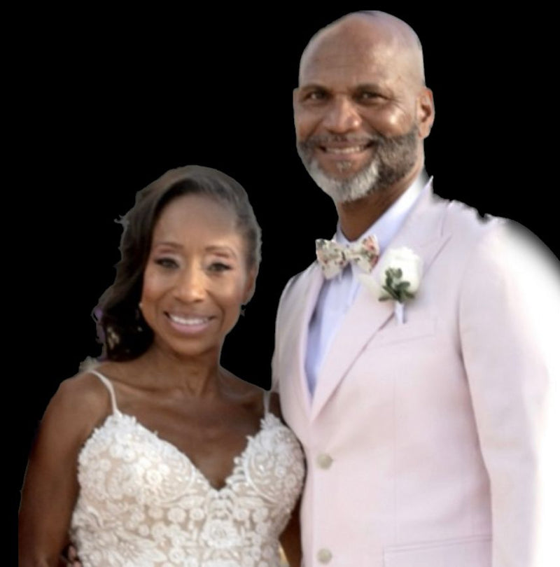 A couple at their 25th anniversary vow renewal by the water, the husband in the Blush Pink 2 Button Suit
