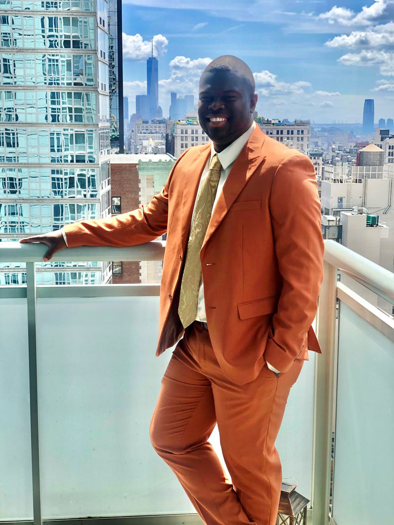 Reginald F. in a burnt orange suit chosen for a wedding theme, on a city balcony